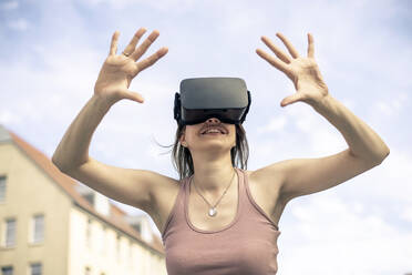 Frau mit Virtual-Reality-Simulator-Brille vor dem Himmel stehend - BFRF02425