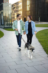 Händchen haltendes Paar mit Hund auf dem Fußweg - MOEF04326