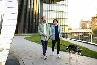 Ehepaar verbringt seine Freizeit mit einem Hund auf einem Fußweg - MOEF04328