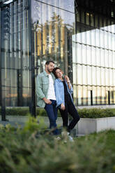 Couple leaning on glass wall of building - MOEF04332