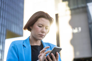 Geschäftsfrau mit kurzen Haaren, die ein Mobiltelefon benutzt - MOEF04354