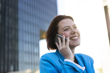 Happy businesswoman contemplating and talking on smart phone - MOEF04357