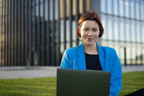 Lächelnde junge Geschäftsfrau mit Laptop - MOEF04388