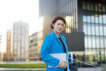 Selbstbewusste Geschäftsfrau mit Tablet-PC vor einem Gebäude stehend - MOEF04396