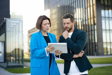 Geschäftsfrau bespricht sich mit einem Kollegen über einen Tablet-PC - MOEF04412