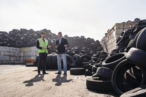 Geschäftsmann und Kollege diskutieren über Gummireifen im Recyclingzentrum - DIGF19187