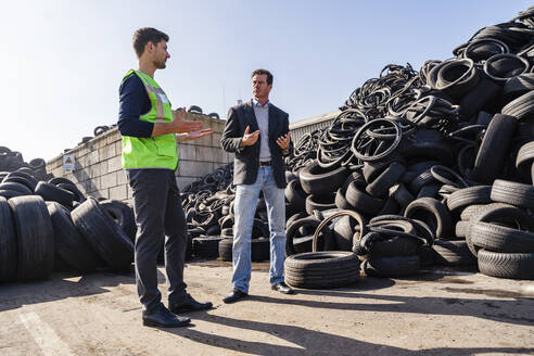 Geschäftsmann und Kollege gestikulieren und diskutieren im Recyclingzentrum - DIGF19192