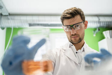 Scientist wearing protective eyewear doing thermolysis experiment in laboratory - DIGF19254