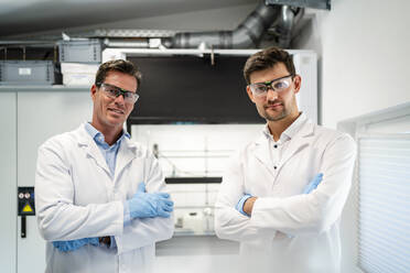 Scientists in lab coats standing with arms crossed in laboratory - DIGF19274