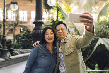 Lächelndes reifes Paar nimmt Selfie durch Mobiltelefon - JCCMF07830