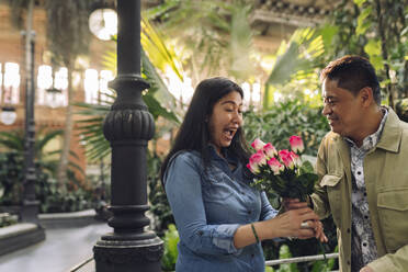 Smiling man giving flowers to woman on Valentine's Day - JCCMF07831