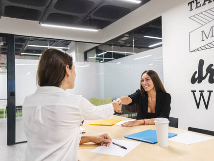 Glückliche Geschäftsfrauen beim Händeschütteln im Sitzungssaal im Büro - AMRF00128