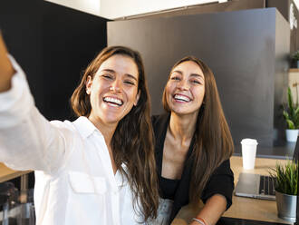 Happy businesswomen talking selfie in office - AMRF00153