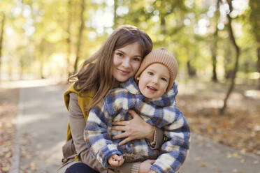 Smiling mother embracing son in park - ONAF00196