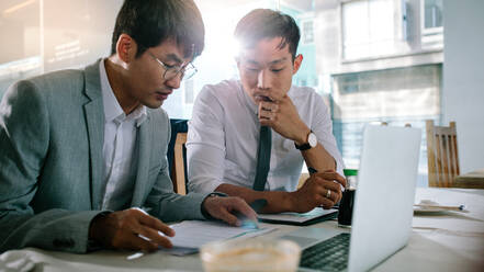 Two business people analysing new project documents in coffee shop. Business professionals going through some paperwork while sitting by at cafe table. - JLPSF23901