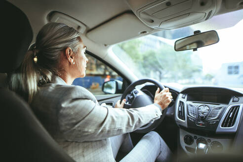 Businesswoman driving a car. Shot from behind of senior female in businesswear driving a car. - JLPSF23906