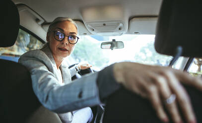 Portrait of senior woman in driving a car in reverse. Senior caucasian female driving a vintage car. - JLPSF23962