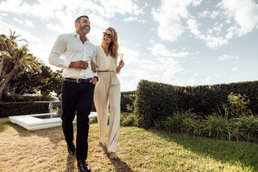 Couple with a glass of wine and enjoying each others company. Man and woman with a drink and having fun outdoors. - JLPSF24040