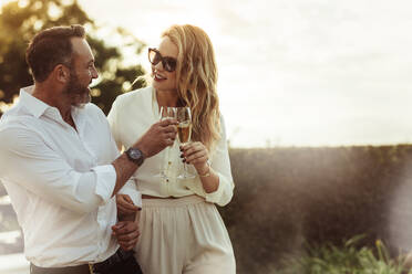 Romantic couple toasting wine glasses outdoors. Beautiful woman clinking wine glass with her boyfriend. - JLPSF24044