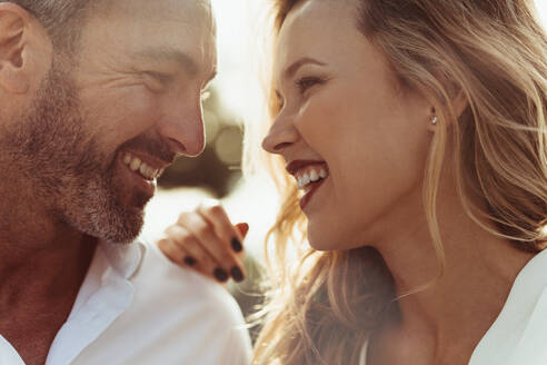 Close up of cheerful man and woman outdoors. Romantic couple together looking at each other and smiling. - JLPSF24052