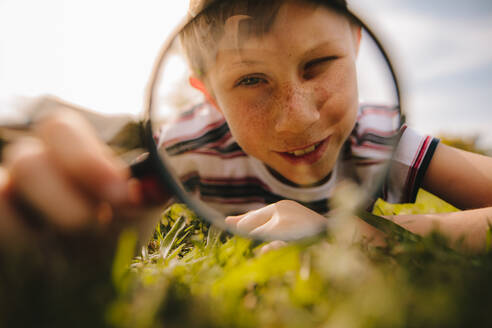 Boy looking through magnifying glass. cute boy exploring with magnifying glass. - JLPSF24123