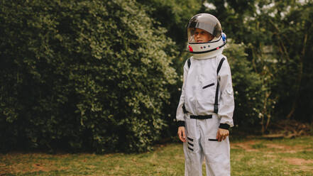 Boy wearing white armor and helmet standing outdoors. Cute boy in space suit and helmet playing astronaut in playground. - JLPSF24133