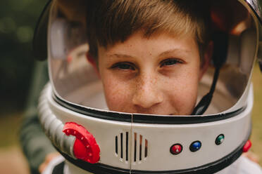 Small boy pretending to be an astronaut wearing a space helmet standing outdoors. Boy playing astronaut with space helmet - JLPSF24135