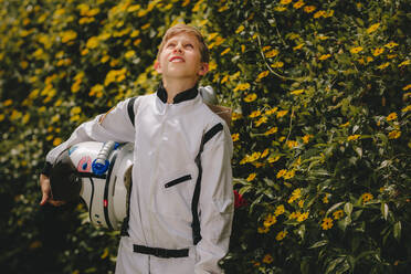 Boy in space suit with helmet walking outdoors and looking up. Cute boy in space suit and helmet playing astronaut outdoors. - JLPSF24140