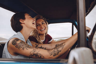 Glückliche junge Frauen lachen und genießen im Auto während einer Autoreise in den Urlaub. Mädchen haben Spaß auf Autoreise. - JLPSF24211