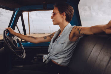 Seitenansicht einer attraktiven Frau am Steuer eines alten Lastwagens, die einen Ausflug in die Natur unternimmt. - JLPSF24220