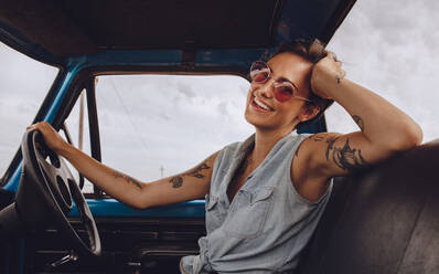 Porträt einer lächelnden jungen Frau mit Sonnenbrille am Steuer eines Autos. Schöne Frau auf einer Autoreise. - JLPSF24221