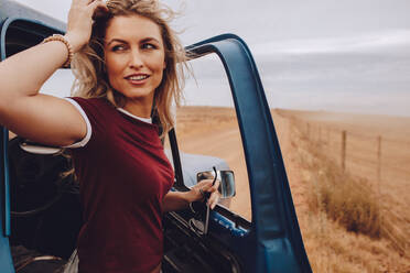 Beautiful woman standing by her car and looking away. Woman on road trip in countryside. - JLPSF24238