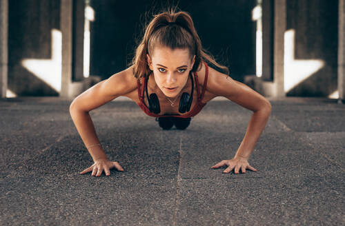 Fit junge Frau macht Push-ups Übungen im Freien. Sportlerin macht Core-Übungen. - JLPSF24299