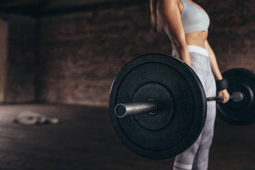 Fitness weibliche Ausübung mit schweren Gewicht Langhantel im Fitness-Club. Fokus auf schweres Gewicht Langhantel in den Händen der weiblichen Athleten. Cropped Schuss mit Kopie Raum. - JLPSF24327