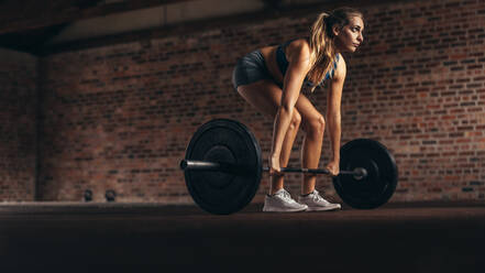 Determined and strong fitness woman training with heavy weights in fitness club. Female athlete doing weight lifting exercise in gym. - JLPSF24329