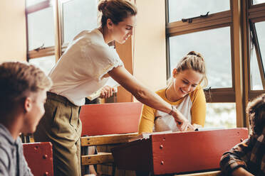 Female teacher assisting a student in the classroom during the lecture. Female professor helping a girl student during a class at high school. - JLPSF24361