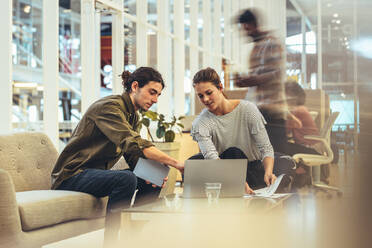 Businesswoman sharing ideas with a client in office. Coworkers looking at a laptop and doing work in office. - JLPSF24407