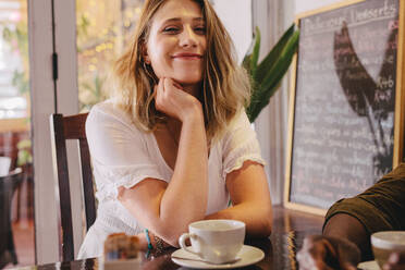 Glückliche junge Frau sitzt mit ihrer Freundin im Café. Entspannte Frau sitzt mit einem männlichen Freund im Café. - JLPSF24429