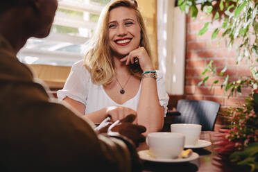 Lächelnde Frau sitzt im Café Tisch hält Hand ihres Freundes. Dating Paar verbringen Qualität Zeit im Café. - JLPSF24445