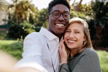 Schönes gemischtrassiges Paar, das ein Selfie im Freien macht. Afrikanischer Mann mit kaukasischer Frau, die ein Selbstporträt machen. - JLPSF24449