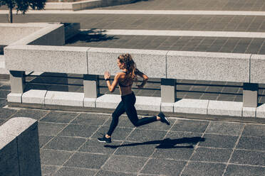 Junge Frau joggt in der Stadt. Weibliche Athletin läuft am Morgen. - JLPSF24468