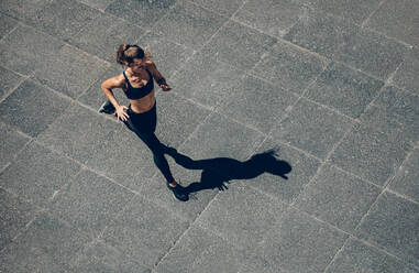 Frau beim Sprint am Morgen im Freien, Blick von oben auf eine Läuferin beim Training in der Stadt. - JLPSF24469