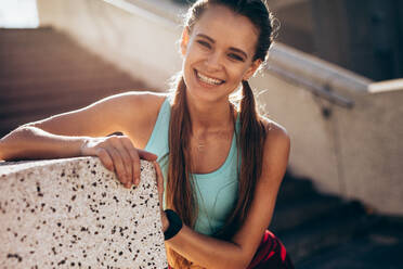 Porträt einer schönen jungen Frau, die im Freien steht und lächelt. Frau, die während des Trainings eine Pause macht. - JLPSF24491