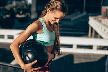 Lächelnde Sportlerin mit Medizinball beim Laufen im Freien. Sportlerin beim Training mit Fitnessball. - JLPSF24497