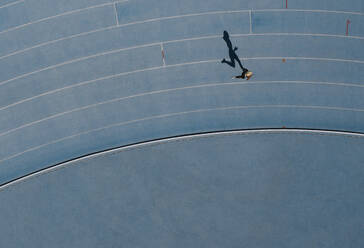 Aerial view of a woman athlete running on athletic track. Overhead view of a female sprinter running on race track in a stadium. - JLPSF24527