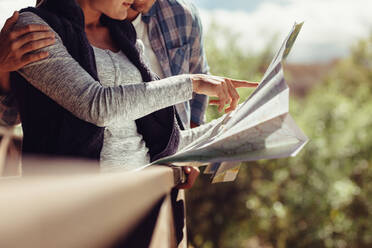 Woman pointing at the map while standing with her boyfriend. Couple looking for travel destination on map. - JLPSF24600