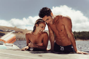 Portrait of young couple hanging on lake dock and smiling. Young man and woman coming out of the lake after swimming. - JLPSF24613