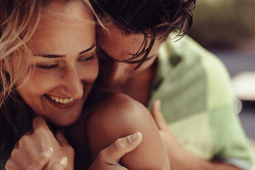 Nahaufnahme einer Frau, die von ihrem in eine Decke gehüllten Freund umarmt wird. Romantisches Paar im Urlaub. - JLPSF24615