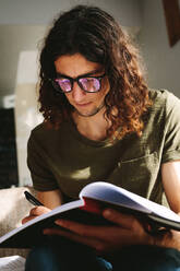 Ein Schüler, der zu Hause lernt und sich Notizen in einem Buch macht. Ein Schüler, der konzentriert und konzentriert lernt. - JLPSF24628