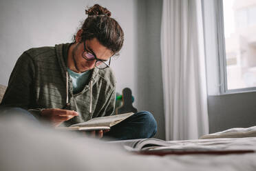 Student, der zu Hause sitzt und für Prüfungen lernt. Junger Mann, der konzentriert Bücher liest und sich auf Prüfungen vorbereitet. - JLPSF24641